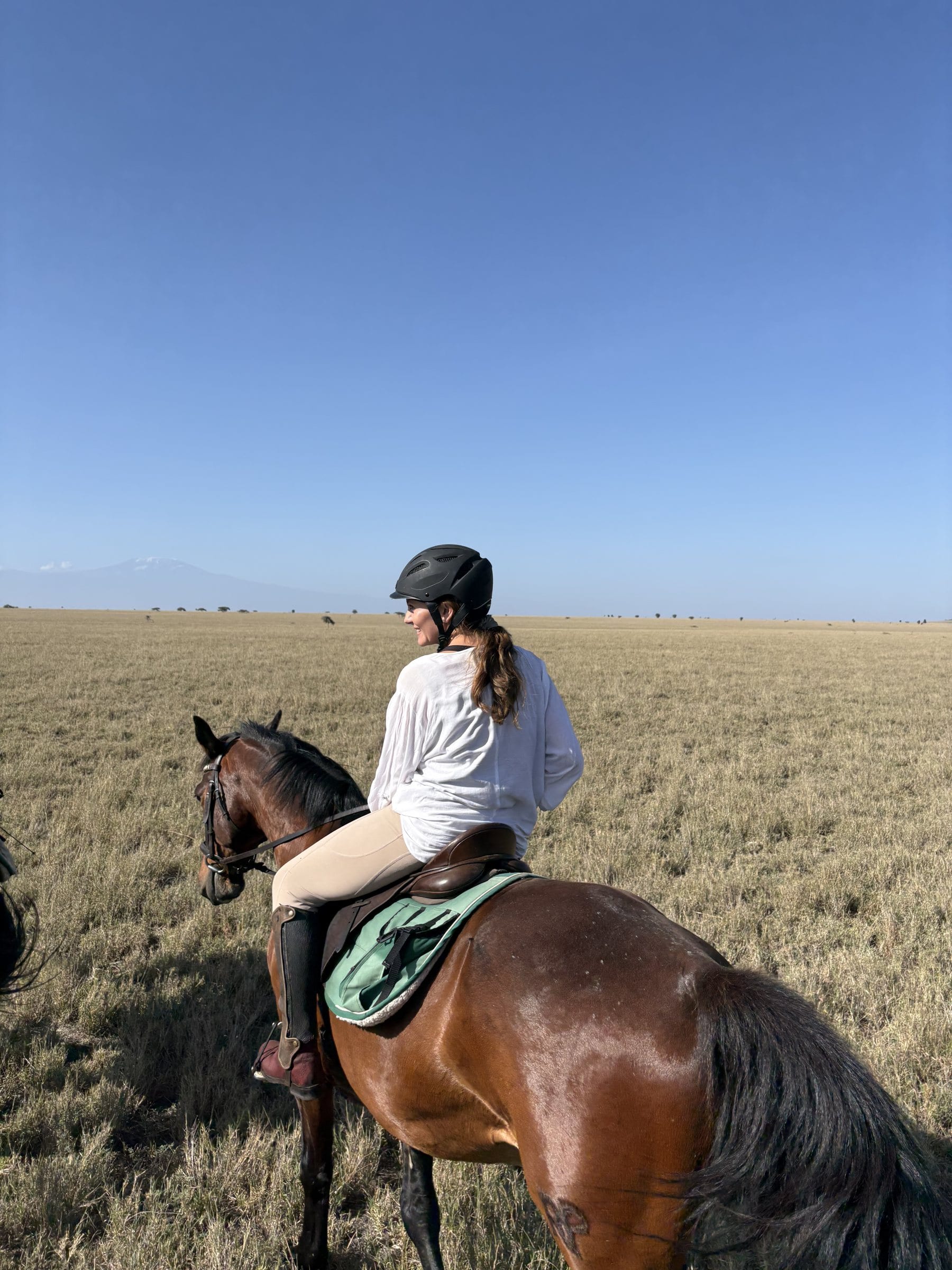 Danielle on horseback on open grassland, looking out across the plain