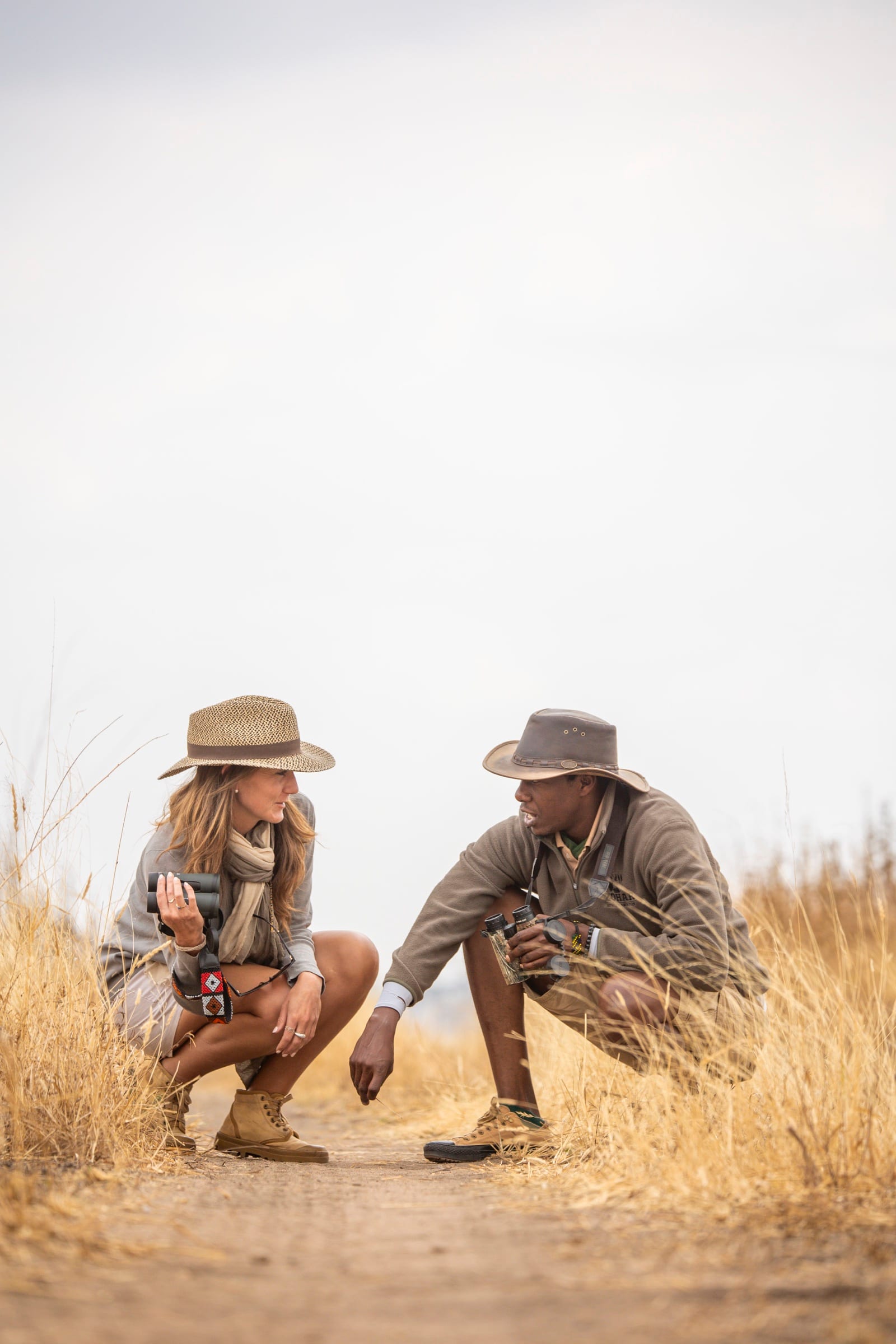 Danielle crouched beside a guide, reading tracks in the sand